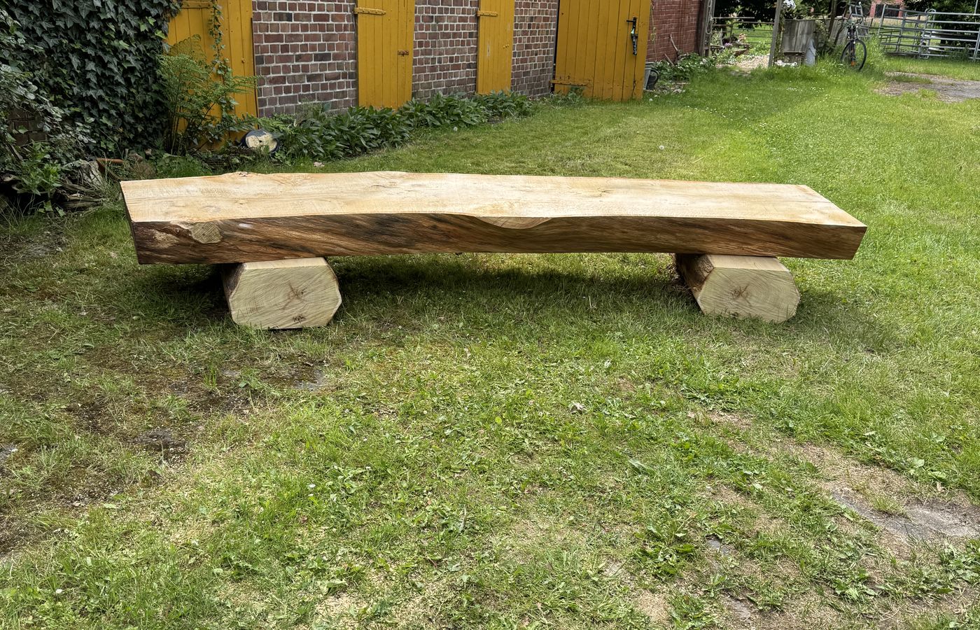 Massive Sitzbank aus einer Bohle im Garten